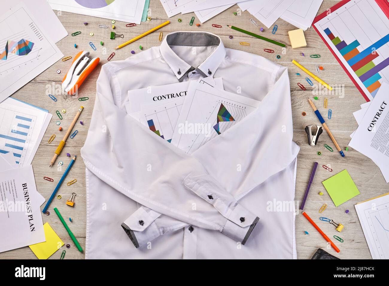Top view white shirt with stationery workdesk stuff. Paperclips staplers pens etc. Stock Photo
