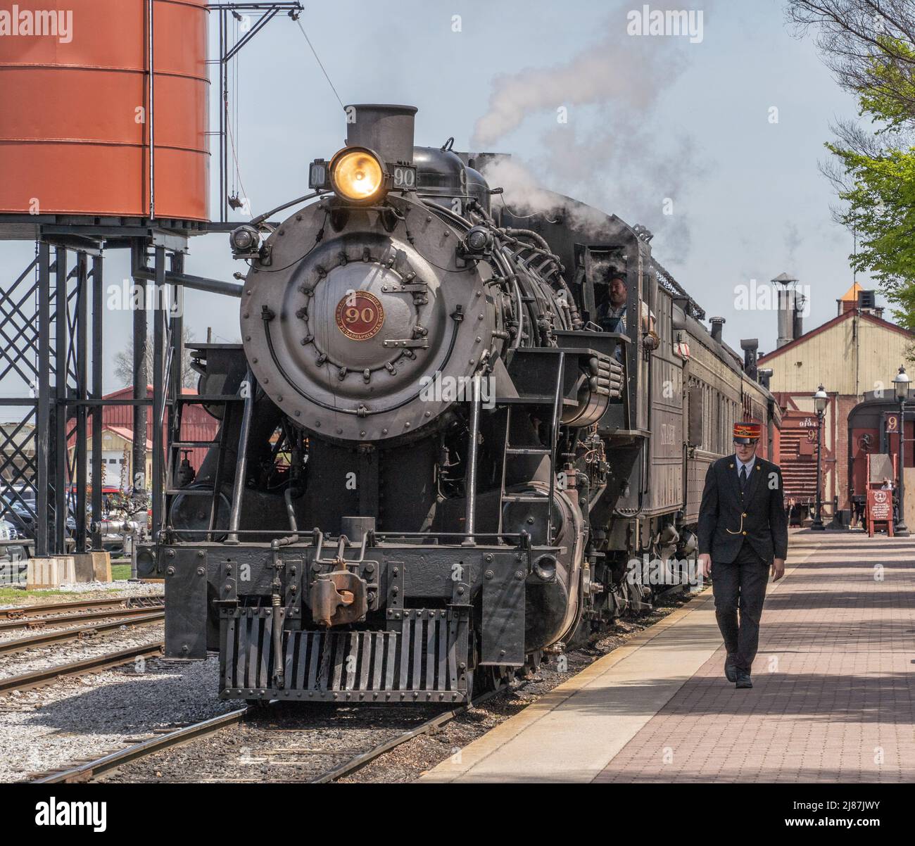 Strasburg Pennsylvania-April 22, 2022: Train conductor walks next to steam train as it arrives station in Strasburg, Lancaster County, Pennsylvania Stock Photo