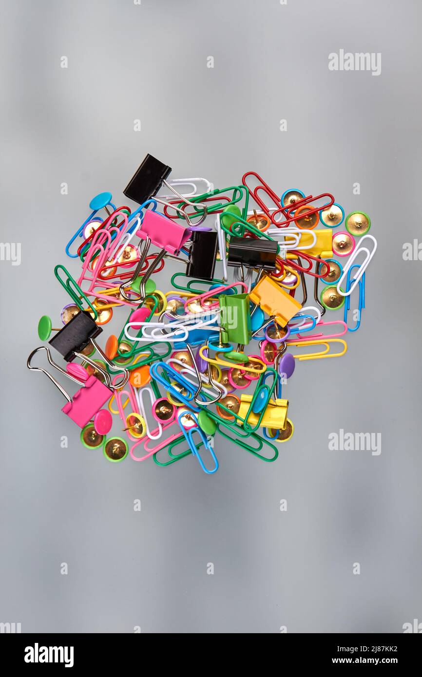 Pile of various paper clipers on blured background. Vertical shot top view. Stock Photo