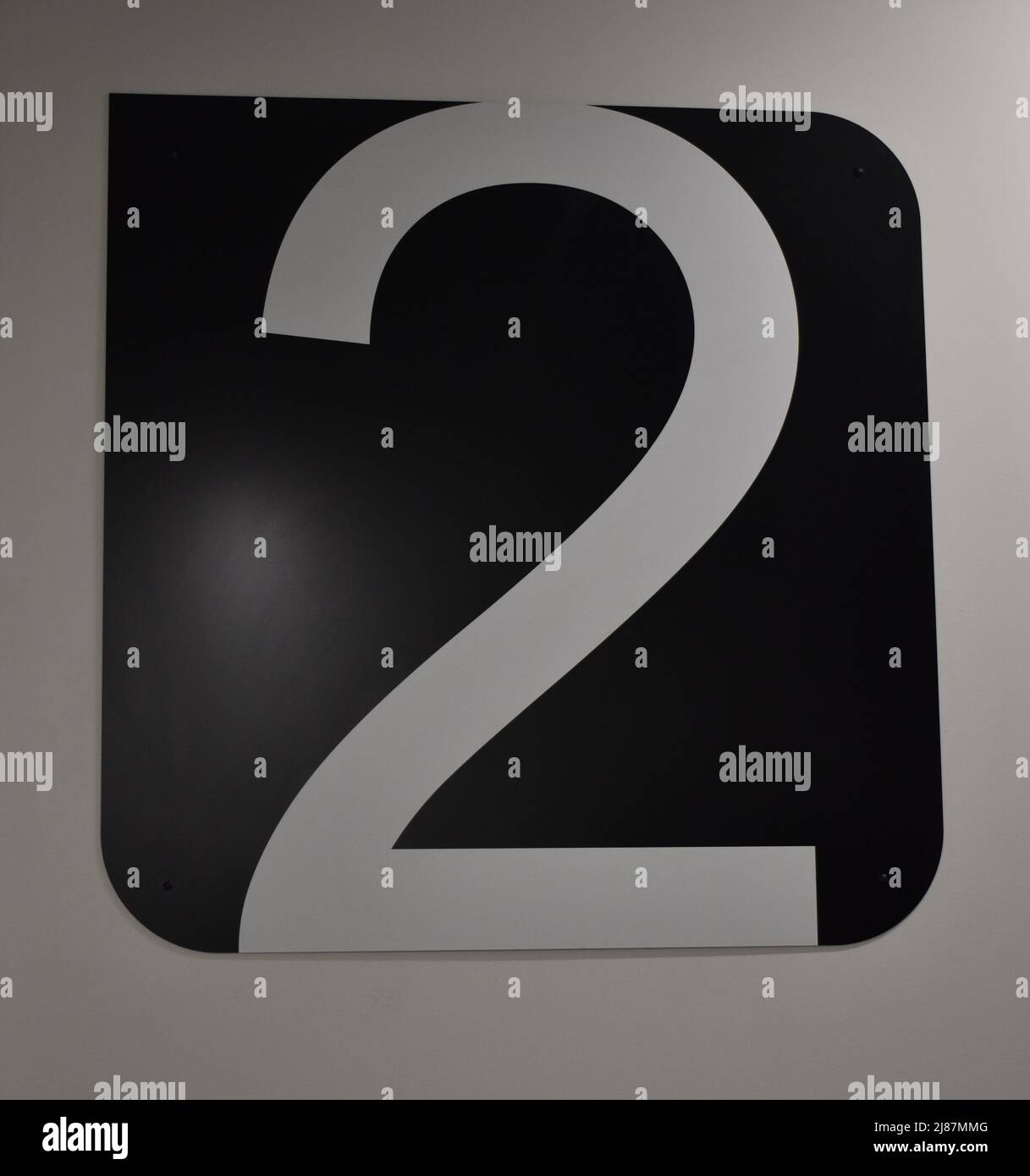 A white number '2' on a black background in a multi-storey car park. Stock Photo
