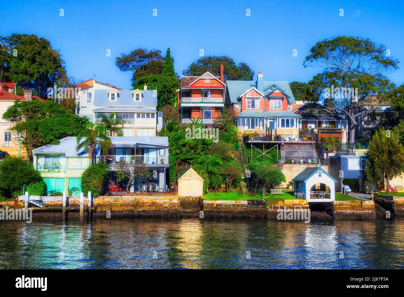 Wealthy waterfront residential properties on Parramatta river in Inner West of Sydney city - skyline under blue sky. Stock Photo
