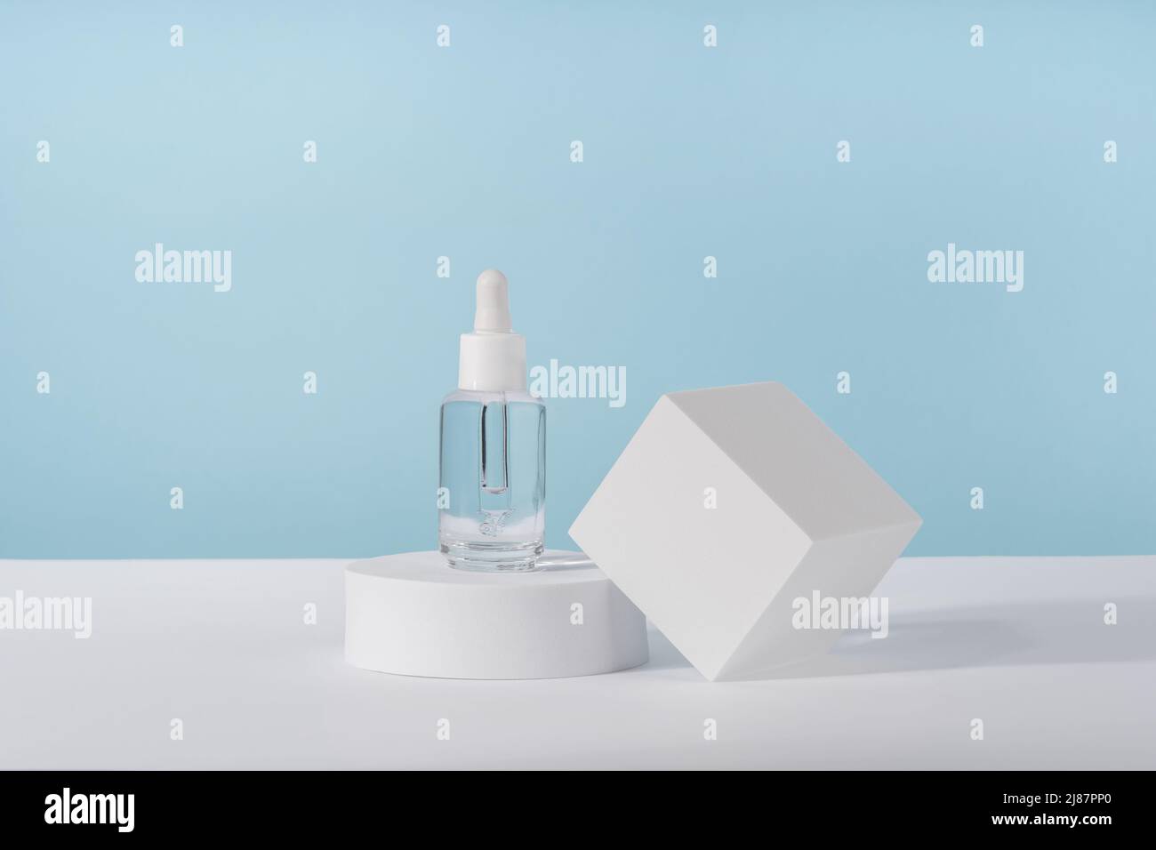 Serum cosmetic bottle with peptides and retinol on platform pedestal on blue background. Oil cosmetics transparent fashion product packaging with Stock Photo