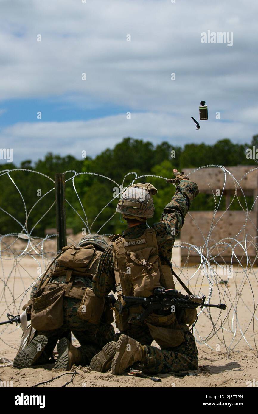U.S. Marines with 2d Combat Engineer Battalion, 2d Marine Division, throw a smoke grenade while breaching concertina wire during the Sapper Leaders Course on Camp Lejeune, North Carolina, May 11, 2022. The Sapper Leaders Course provides combat engineer squad leaders with the technical and tactical proficiency required to provide mobility, counter mobility and survivability to infantry company commanders. (U.S. Marine Corps photo by Lance Cpl. Ryan Ramsammy) Stock Photo