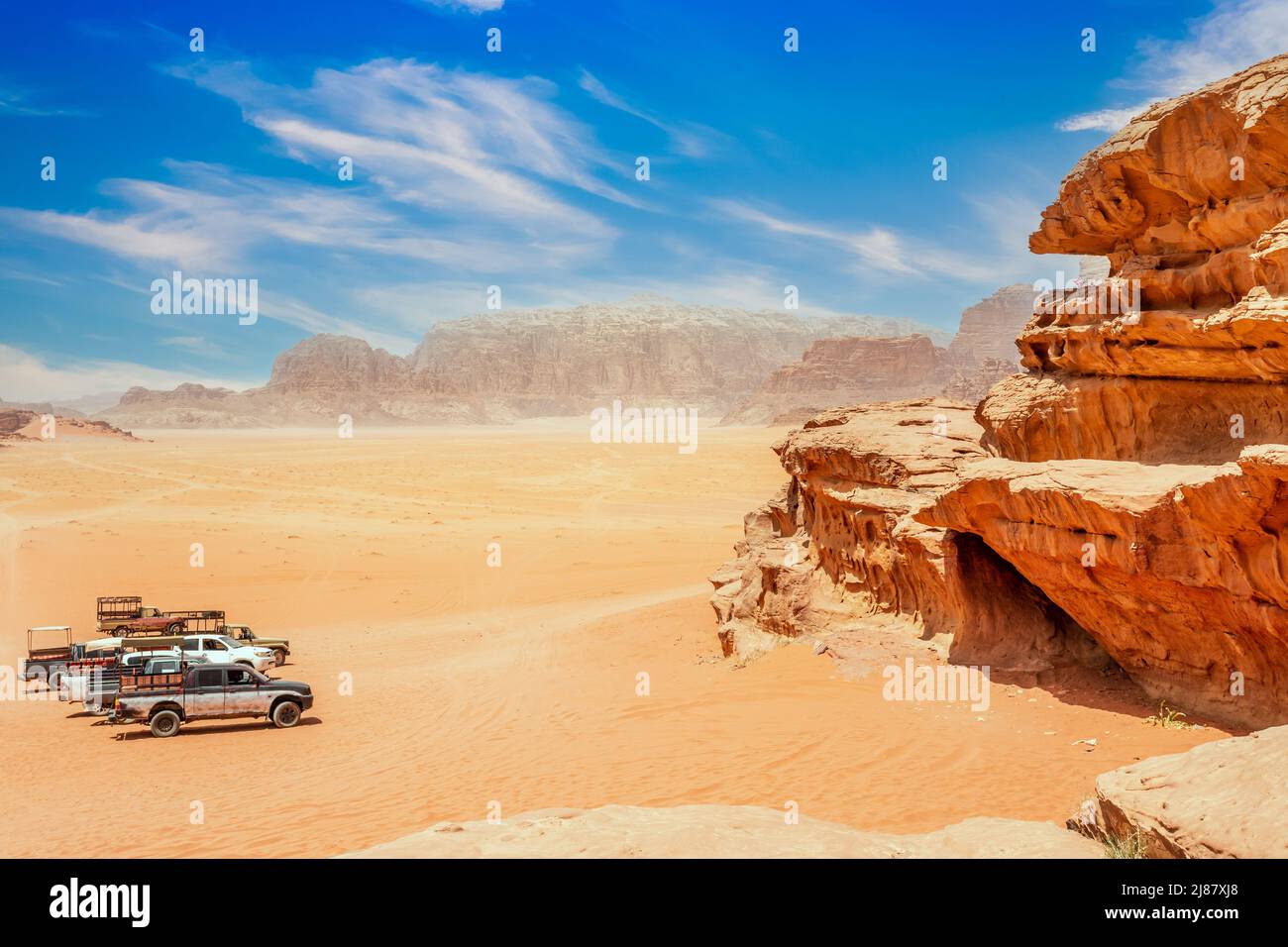 Orange sands and rocks of Wadi Rum desert with cars in the foreground, Jordan Stock Photo