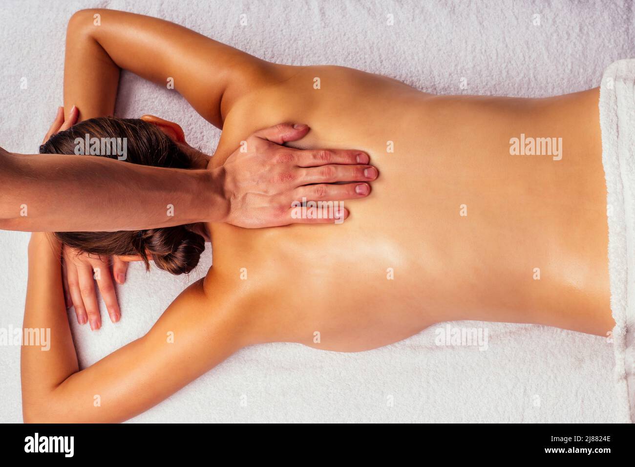 woman lying on the table and getting ayurvedic massage with organic oil or honeyed in dark room.massagist making yoga massage Stock Photo
