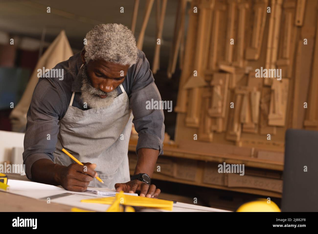 African american mature carpenter drawing diagram while working in woodworking workshop Stock Photo