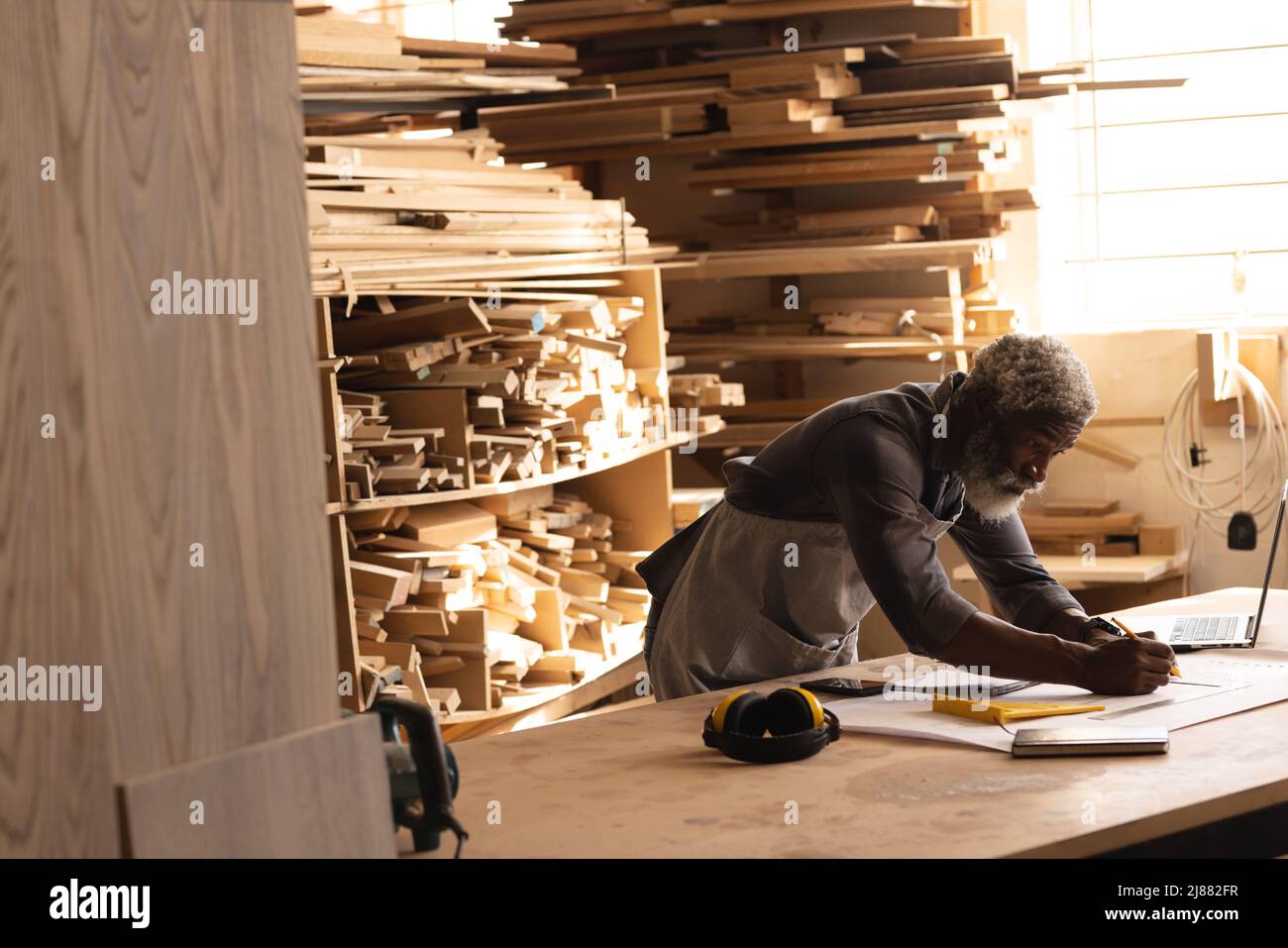 African american mature carpenter drawing diagram while working in workshop Stock Photo