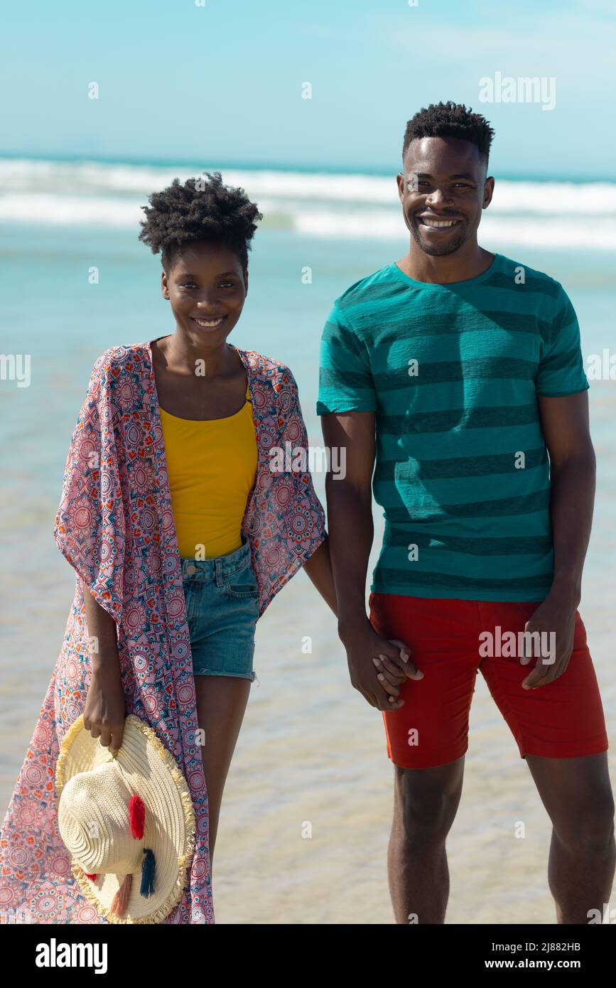 Portrait of smiling african american young couple holding hands and ...