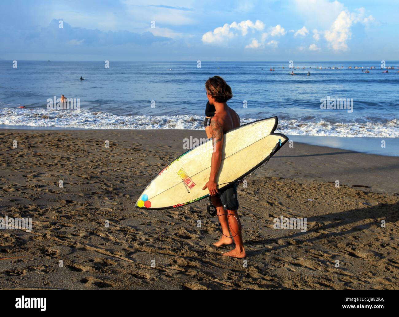 A local Indonesian male surfer walking along Batu Bolong Beach in