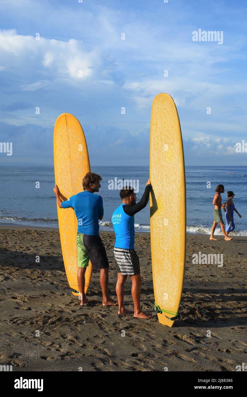 Two male caucasian surfers standing at Batu Bolong Beach in Canggu, Bali, Indonesia carrying their long boards or malibu surfboards. Stock Photo