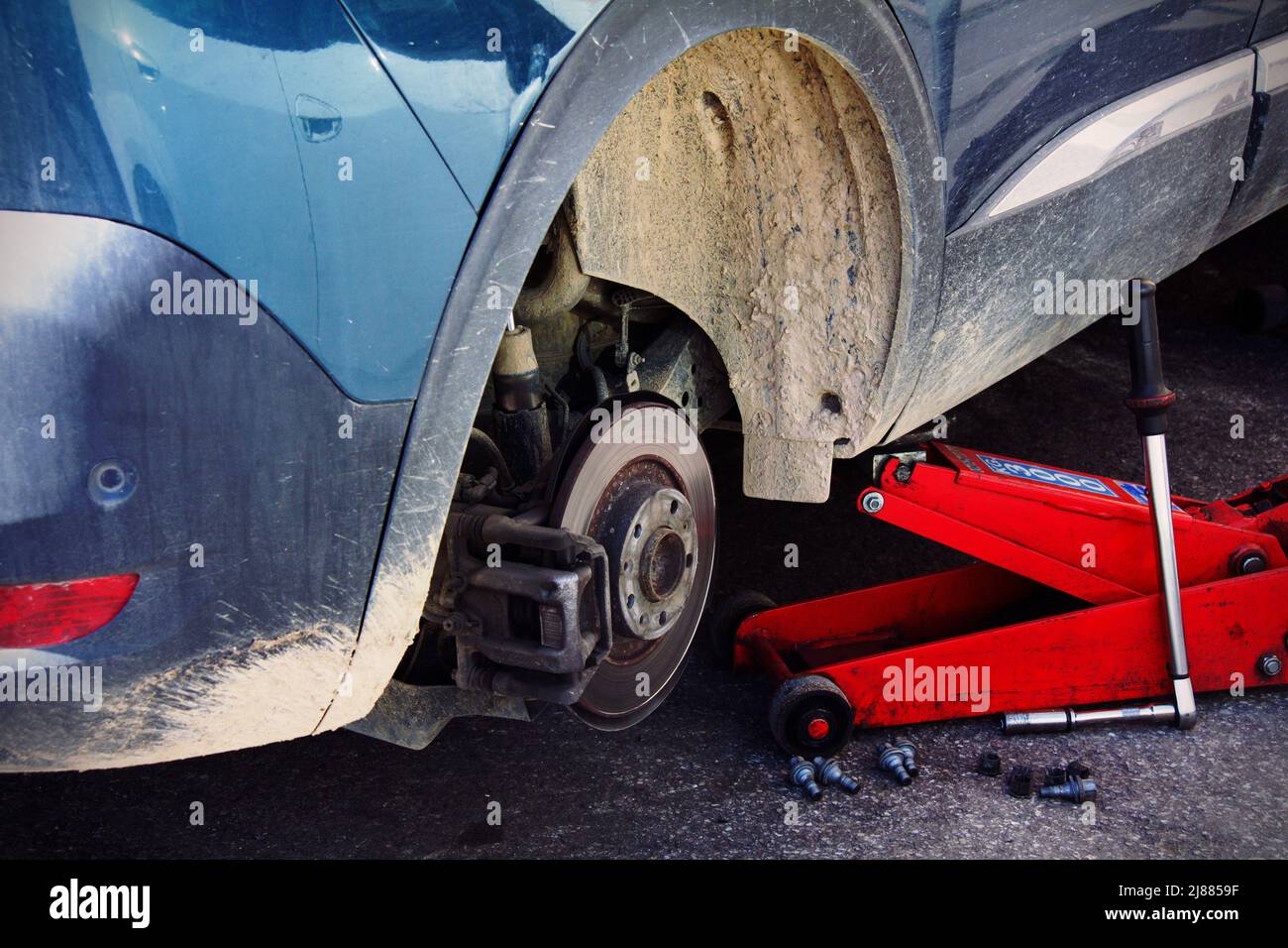 Red lifter lifting a car during replacement Stock Photo Alamy