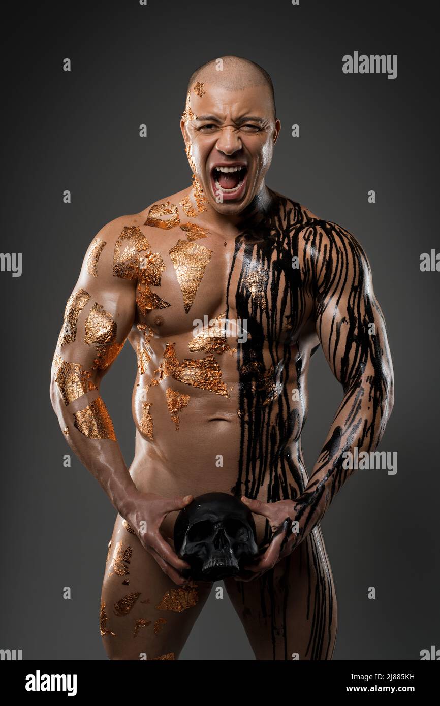 Naked man with painted body and skull in studio Stock Photo