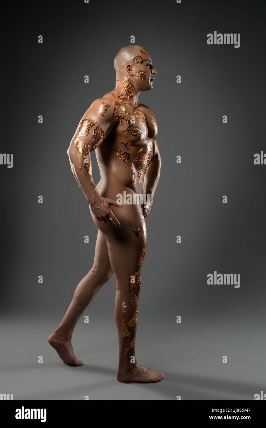 Nude muscular man golden body art posing in studio Stock Photo