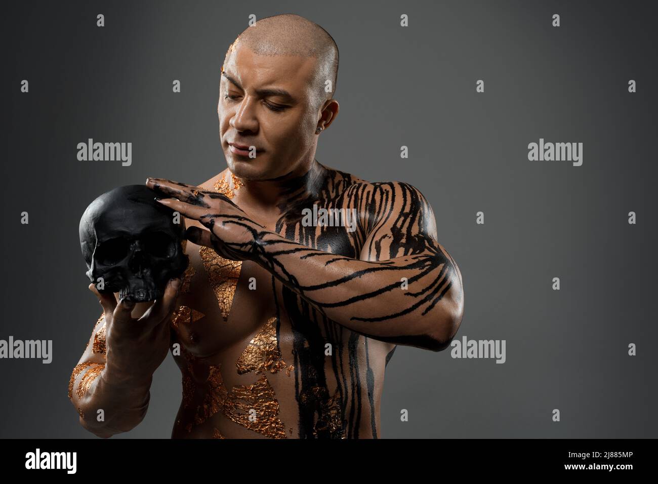 Muscular man in paints and with skull in studio Stock Photo