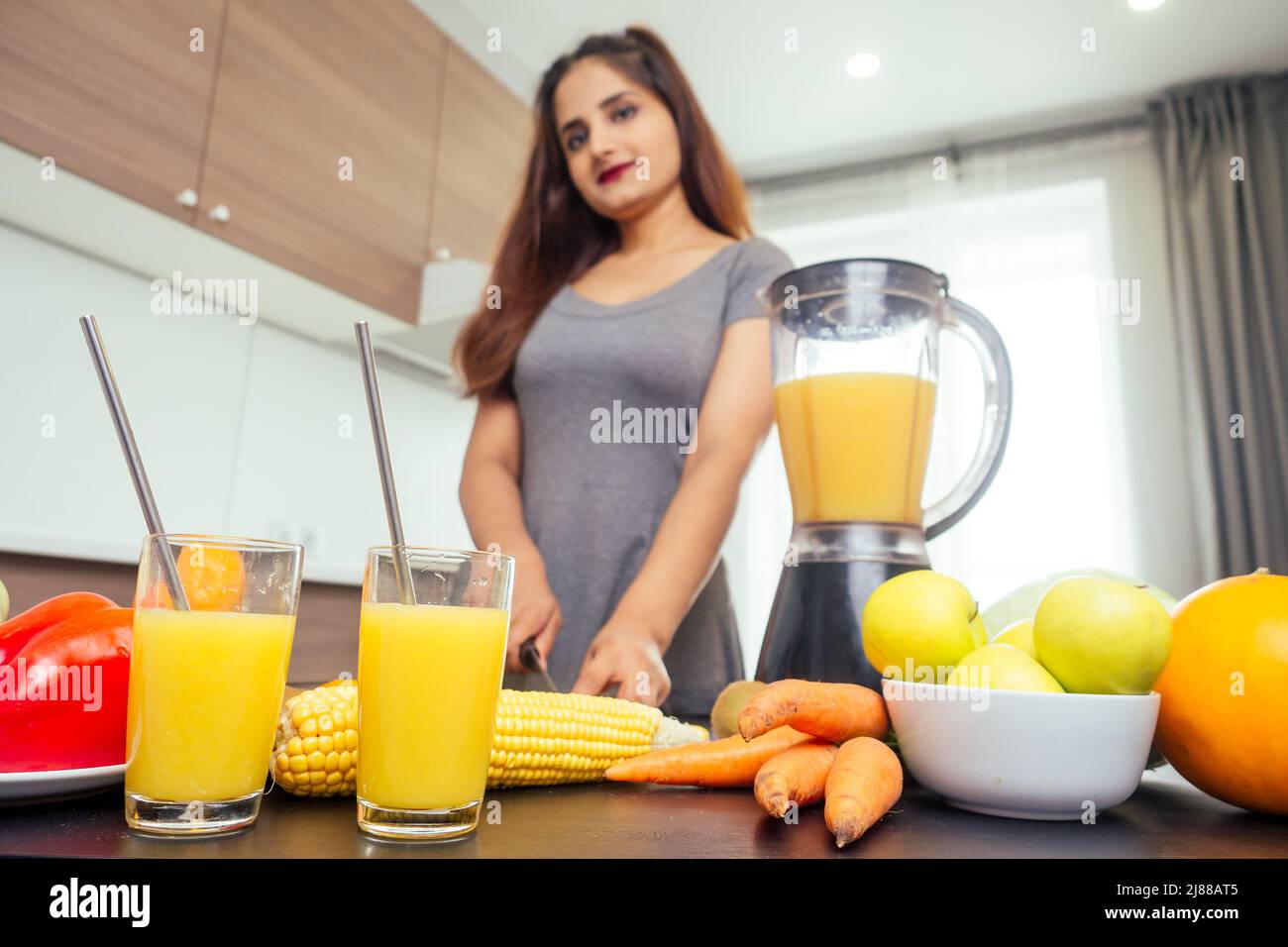 Young happy indian woman making healthy drinks on juicer smoothie jar in modern home Stock Photo