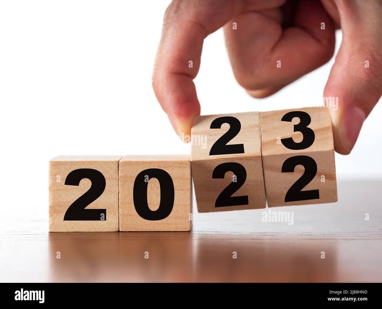 New Year concept from 2022 to 2023. Man's hand change wooden cubes on white table. Change, success and new business plans concept Stock Photo