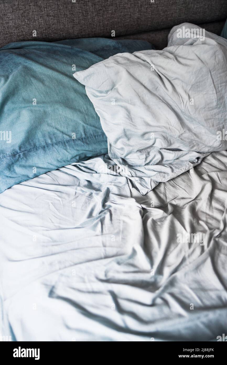 messy bed with light blue quilt cover and sheets looking crumpled and