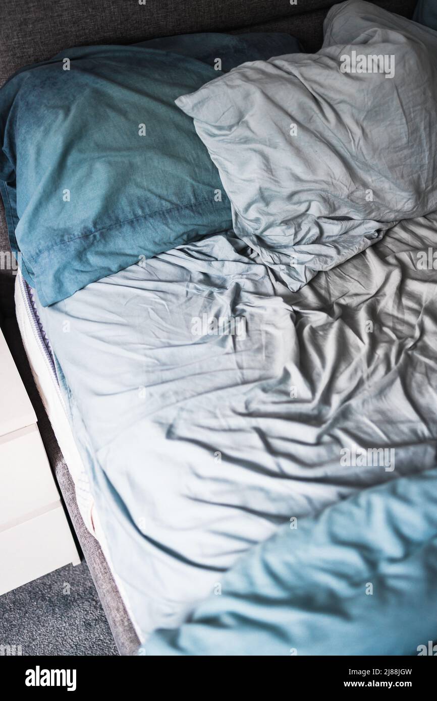 messy bed with light blue quilt cover and sheets looking crumpled and
