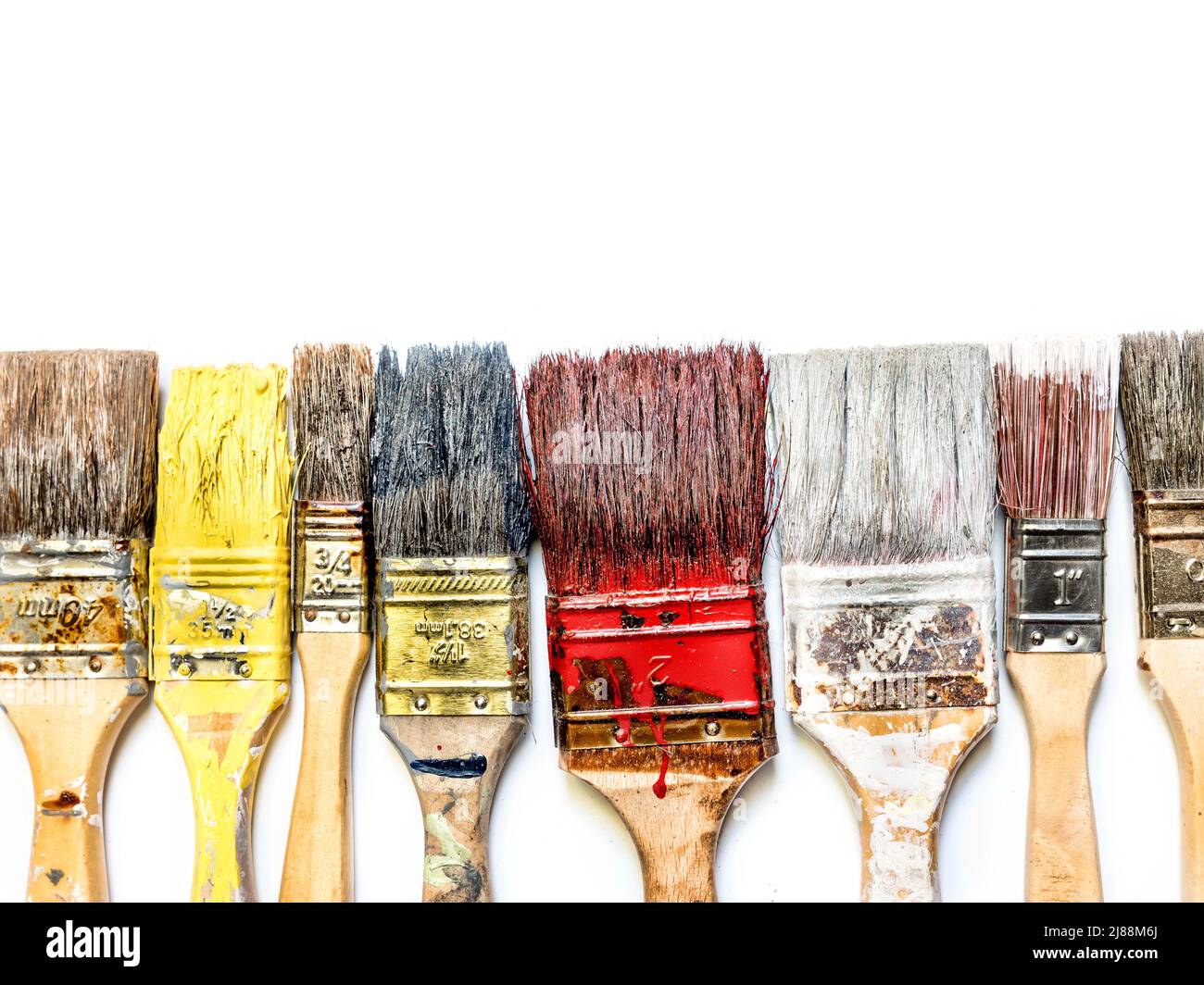 Used and dried paint brushes laid in a row shot from above on white Stock Photo