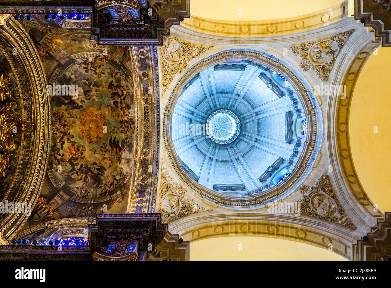 The main chapel dome and its vaulted ceiling painted by Juan Espinal in the 18th century with a rapresentation of the Celestial Glory presided over by the Holy Spirit in the form of a dove - Collegiate Church of the Divine Savior - Seville, Spain Stock Photo