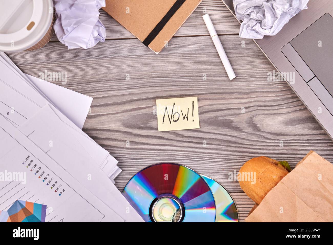 Top view flat lay office desk with now word on the note. Gray desk
