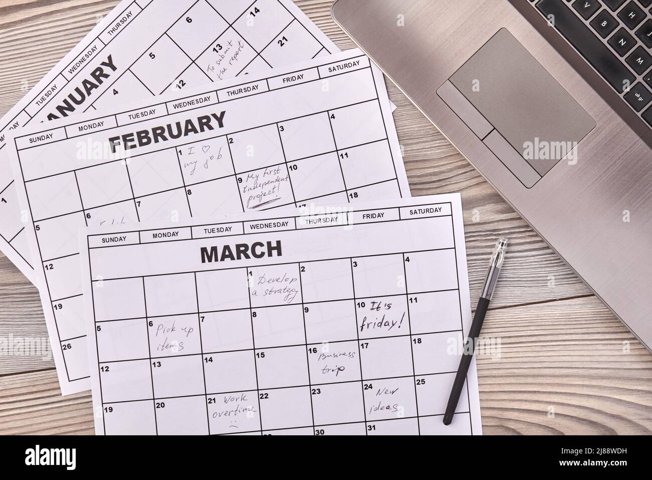 Paper calendars with pen and laptop pc. White desk background Stock
