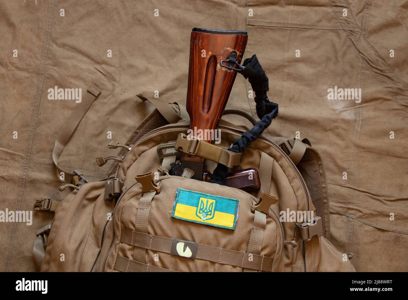 Military green backpack with the flag of Ukraine and a machine gun on a green background, a backpack of a Ukrainian soldier, the war in Ukraine 2022 Stock Photo