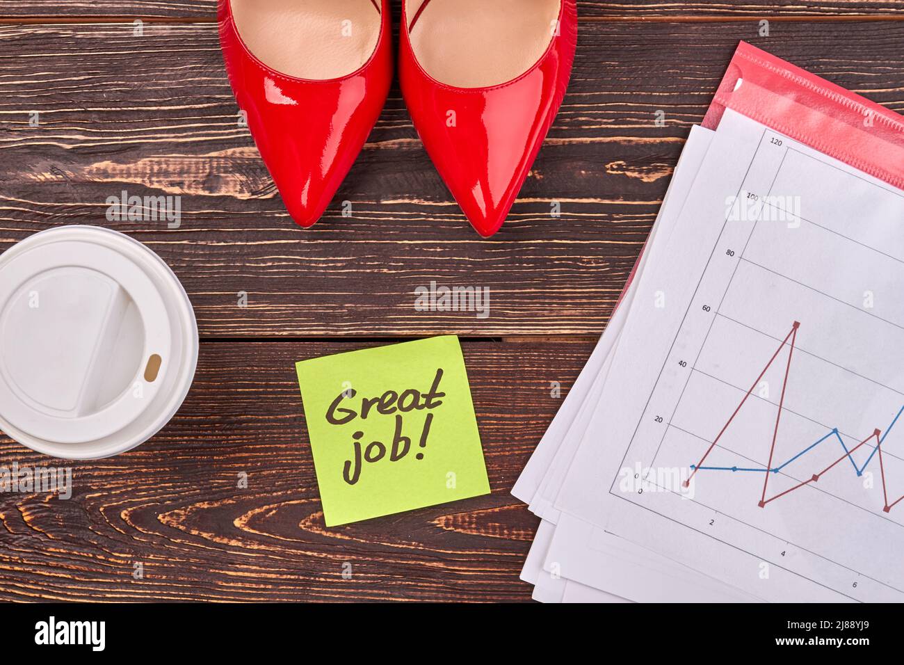 Top view flat lay red shoes and plastic cup. Sticky note with great job handwriting on brown wood. Stock Photo