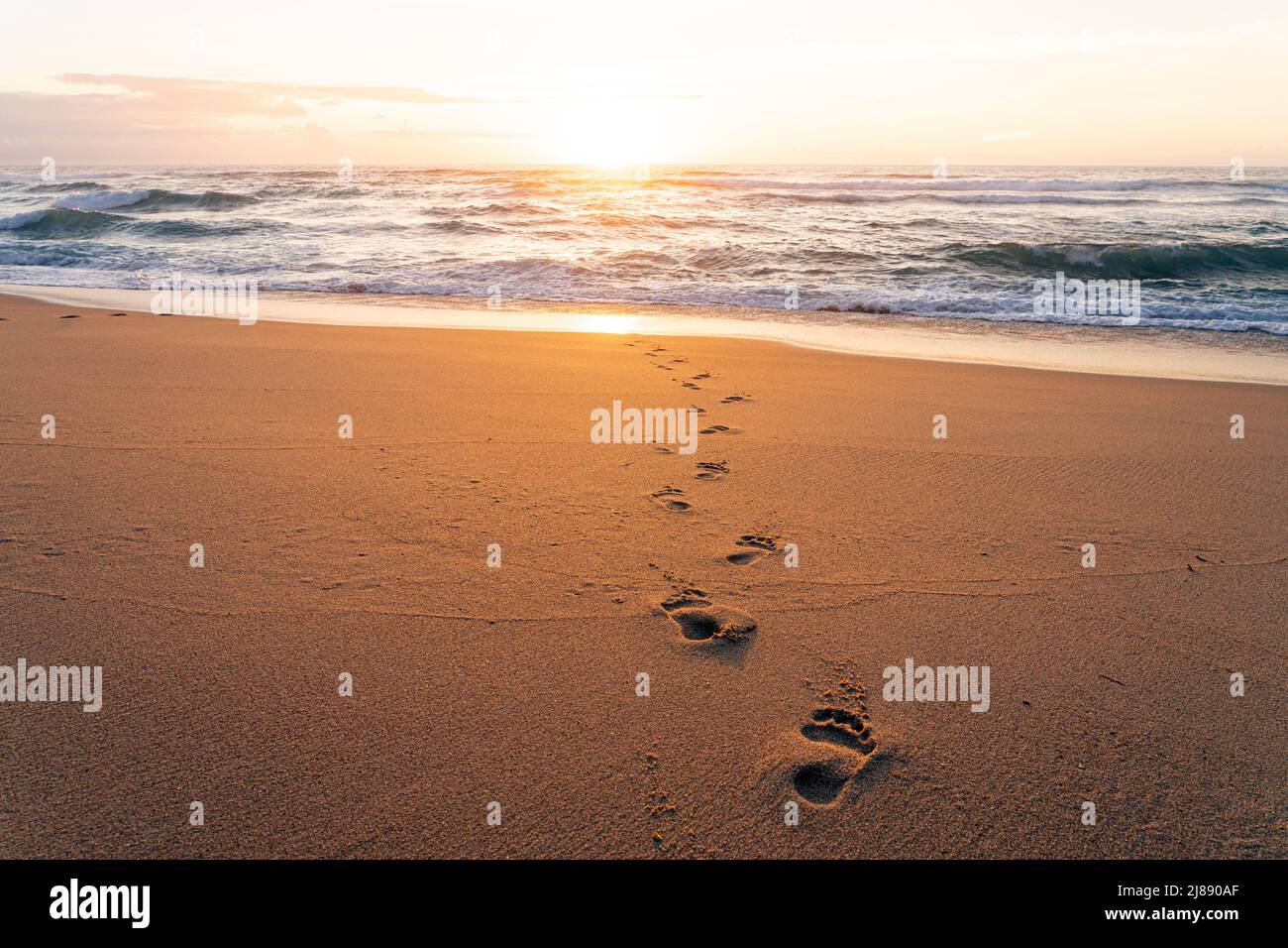 Footprints on the sand of a beach at sunset Stock Photo