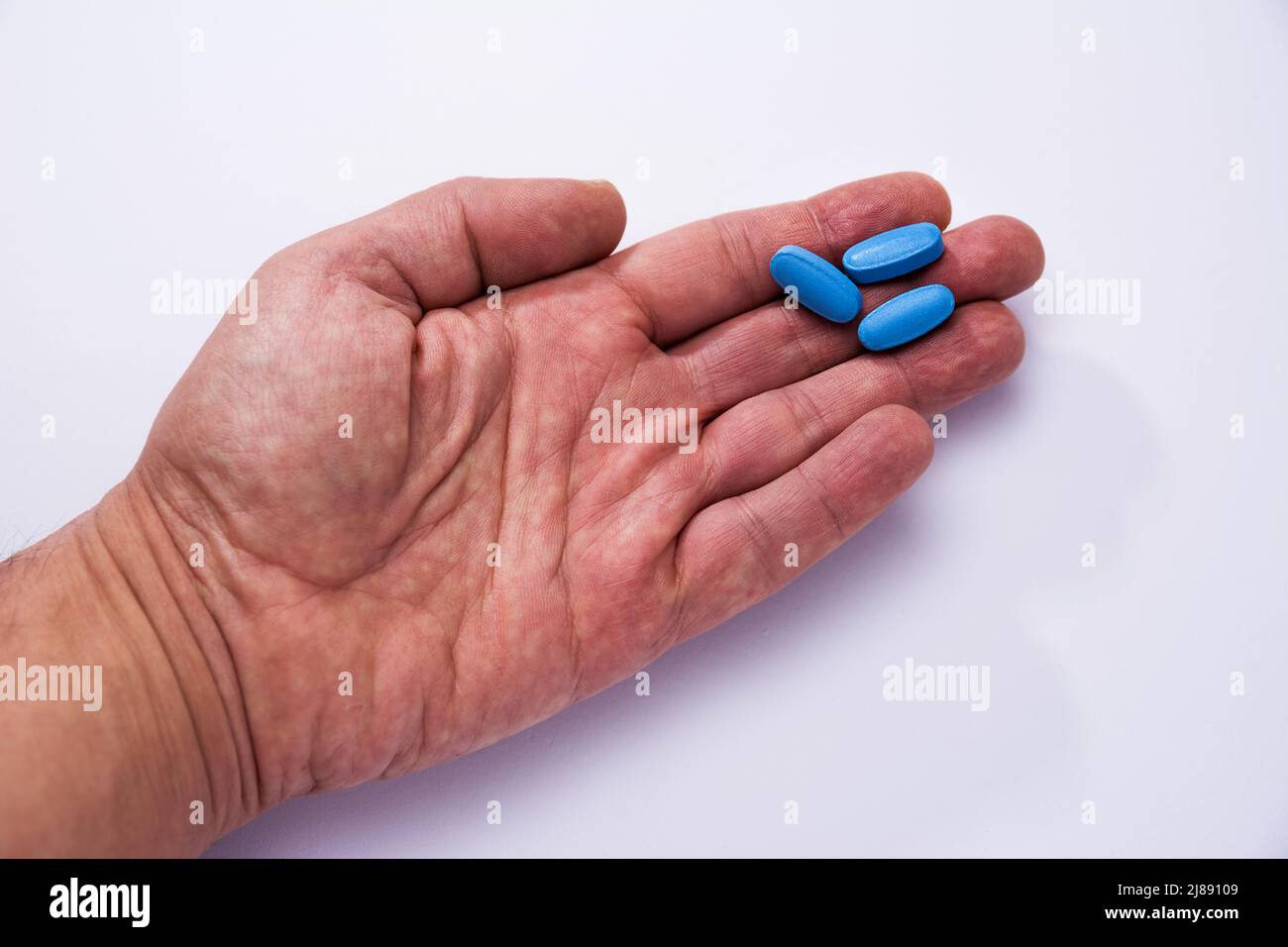 Male hand showing three blue pills Stock Photo
