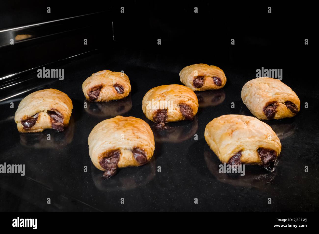 Seven baked mini homemade buns with chocolate filling in electric oven