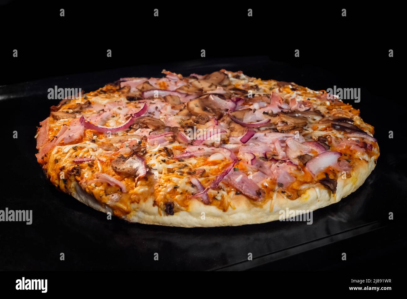 Baked homemade pizza in electric oven at home, black background Stock