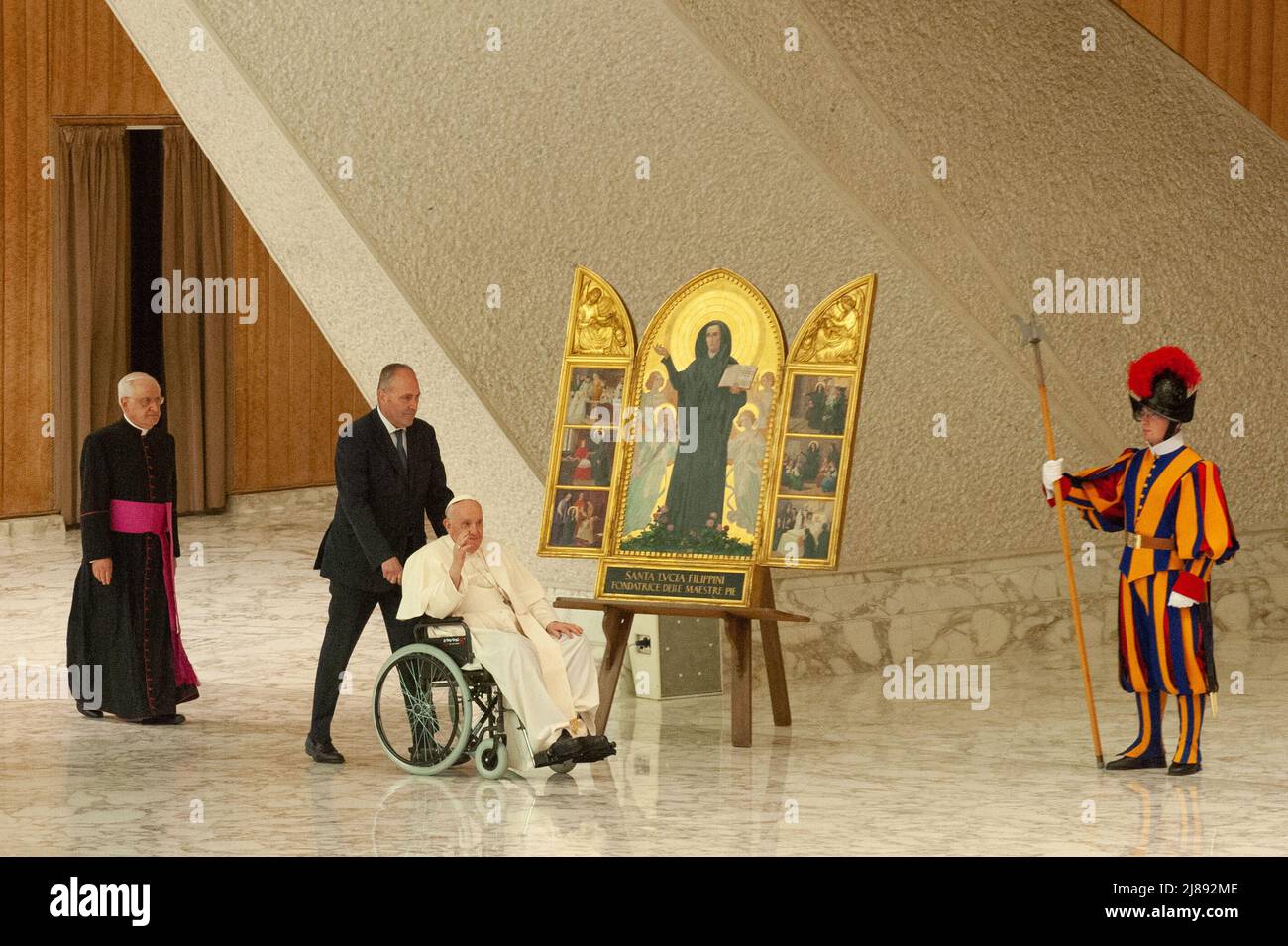Italy, Rome, Vatican, 22/05/14. Pope Francis, arrives in a wheelchair pushed by his butler Pierluigi Zanetti, to leads a special audience to pilgrims from the Istituto Maestre Pie Filippini and the Dioceses of Viterbo and Civitavecchia-Tarquinia, on the occasion of the 350th anniversary of the birth of St. Lucia Filippini, in the Paul VI Hall.Papa Francesco, in sedia a rotelle e spinto dal suo maggiordomo Pierluigi Zanetti, conduce un'udienza speciale ai pellegrini dell'Istituto Maestre Pie Filippini e delle Diocesi di Viterbo e Civitavecchia-Tarquinia, in occasione del 350° anniversario della Stock Photo