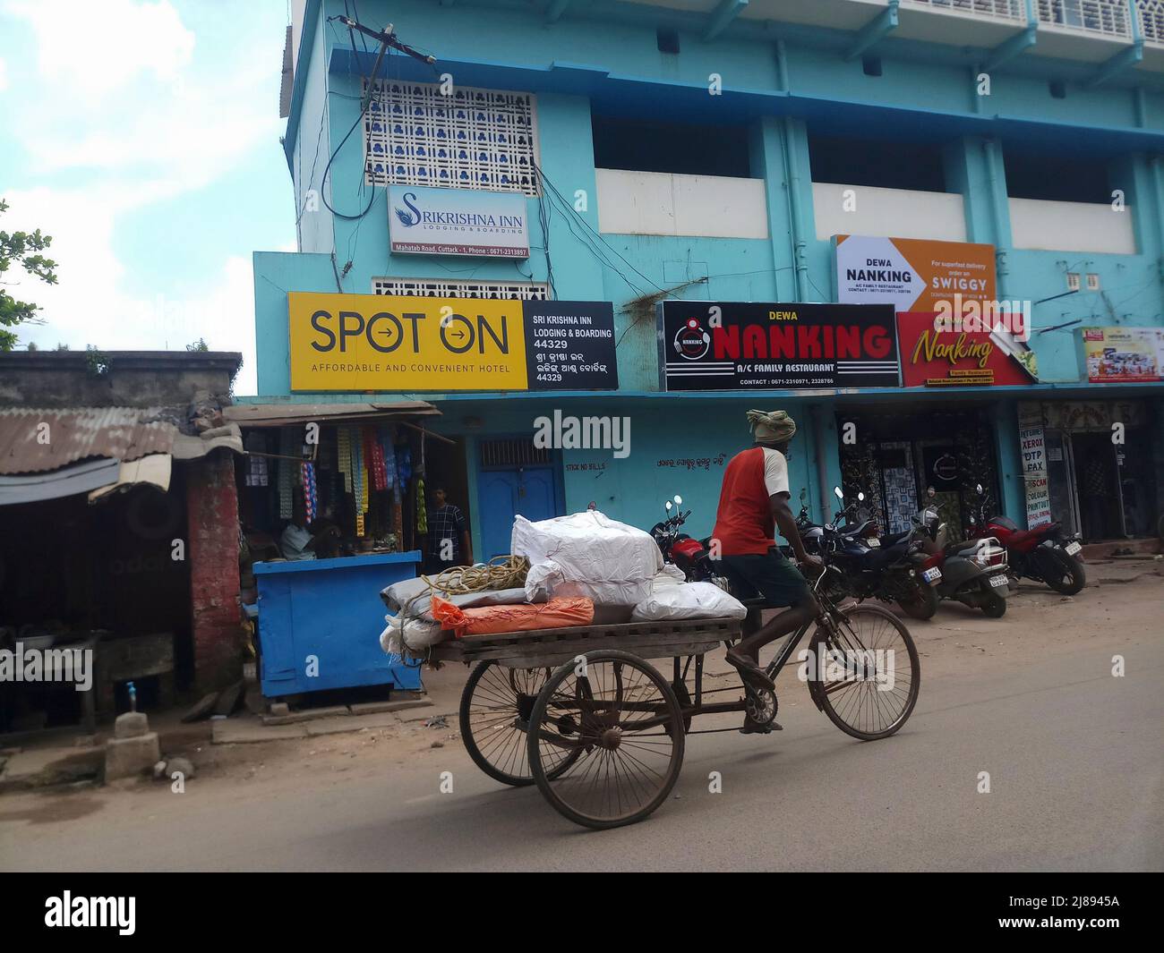 Cuttack, Odisha, India - 24th July 2019 : View of road of Cuttack city, Van rickshaw puller carrying goods. Stock Photo