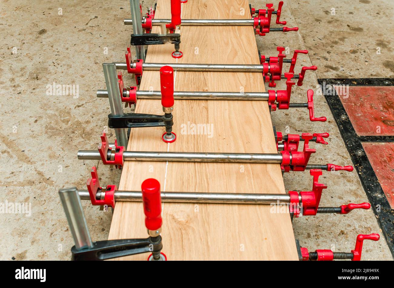 Close up of carpenter fastening board with clamps. Carpentry workshop Stock Photo