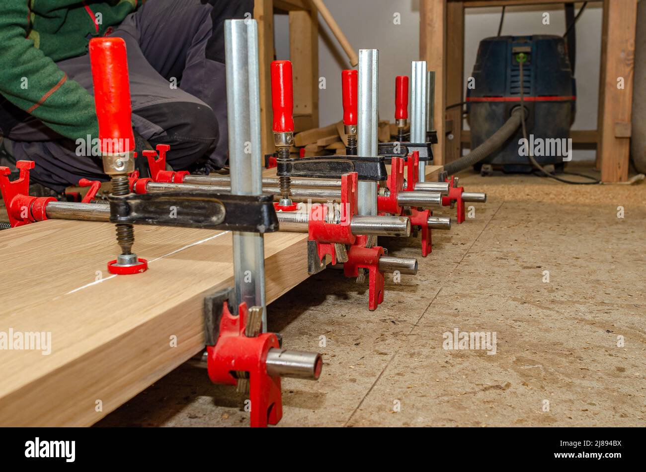 Board with clamps in carpentry workshop. Joinery work. Carpenter Stock Photo