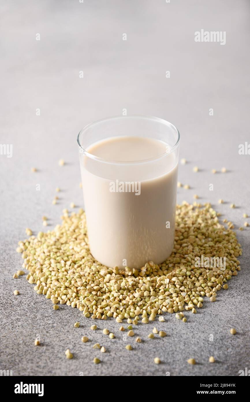 Vegan green buckwheat milk in glass on gray background. Vertical format