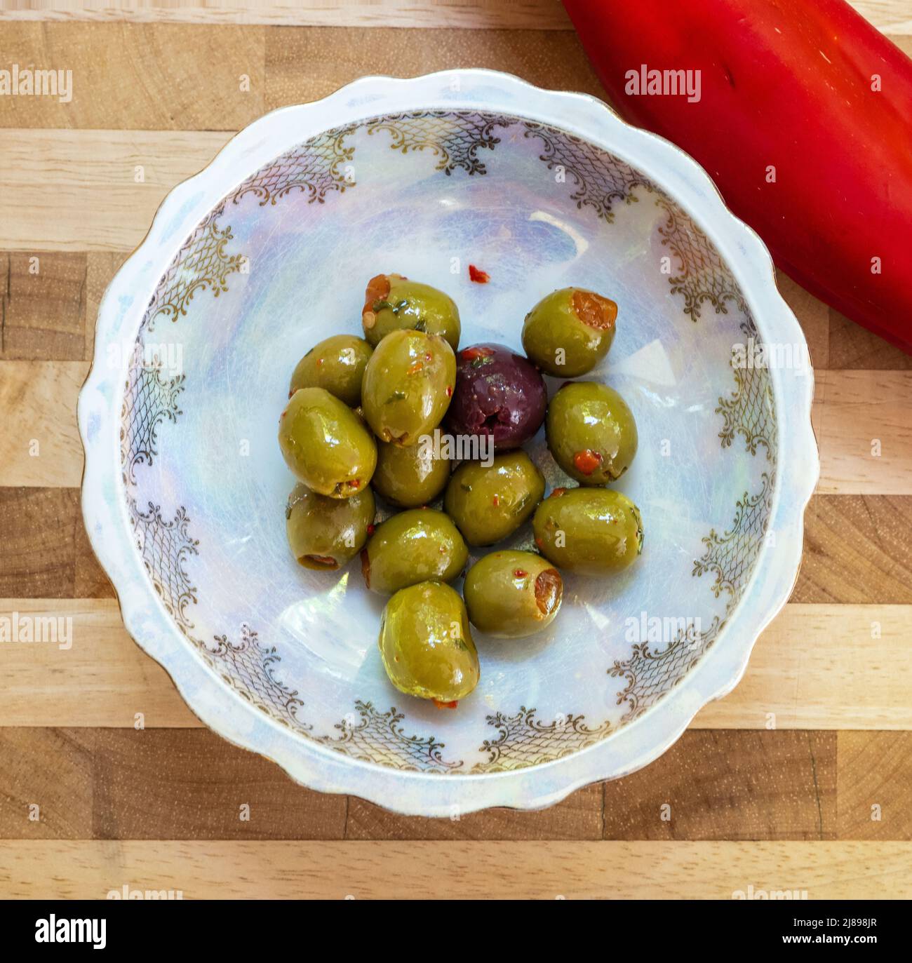 porcelain dish containing green and black olives with a red chilli