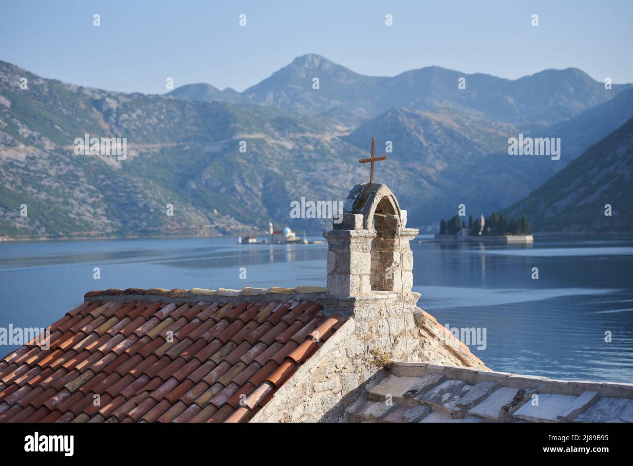 Cross on the church roof against sea and mountains in Montenegro Stock Photo