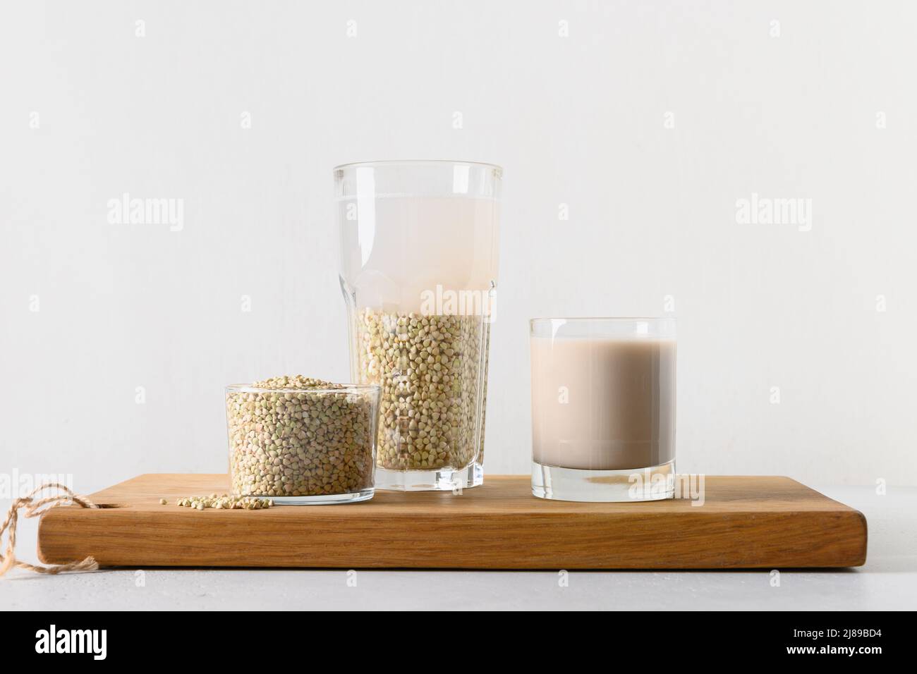 Cooking vegan cereal green buckwheat milk on white background. Healthy plant based milk replacer and lactose free. Stock Photo