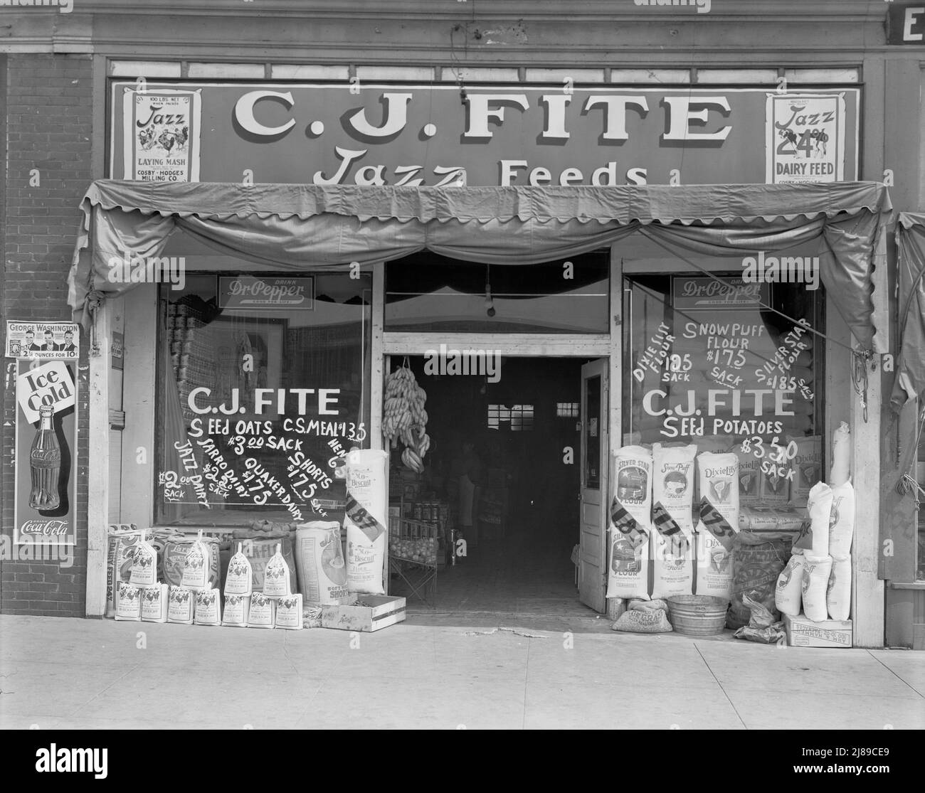 Alabama feed store front. ['C.J. Fite - Jazz Feeds', advertising Coca Cola, Dr. Pepper; George Washington tobacco. Selling Jazz growing mash and all mash starter; seed oats; flour; potatoes; bananas; Silver Star, Snow Puff and Dixie Lily flour, Stock Photo