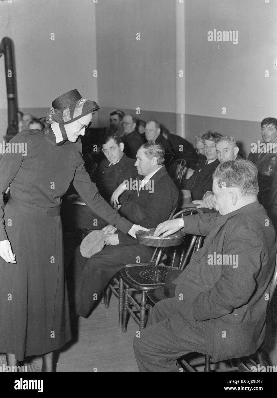 Meeting opens with taking the collection. Army contributes (about one dollar and fifty cents) again, as well as the audience. Salvation Army, San Francisco, California. Stock Photo