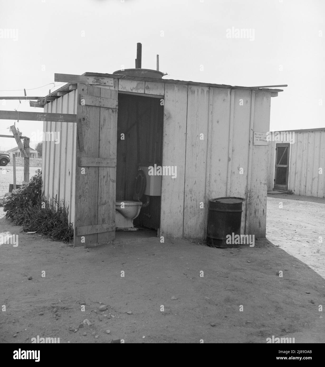 Toilet for ten cabins, men, women, and children. In Arkansawyers auto camp. Greenfield, California. [Sign: 'Do not throw cans in garbage']. Stock Photo