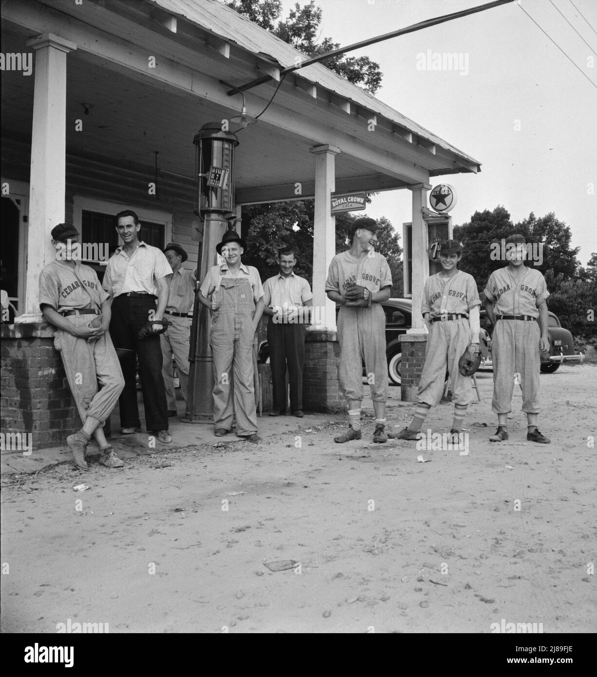 Fourth of July, near Chapel Hill, North Carolina. Rural filling stations become community centers and general loafing grounds. The men in the baseball suits are on a local team which will play a game nearby. They are called the Cedargrove Team. Stock Photo