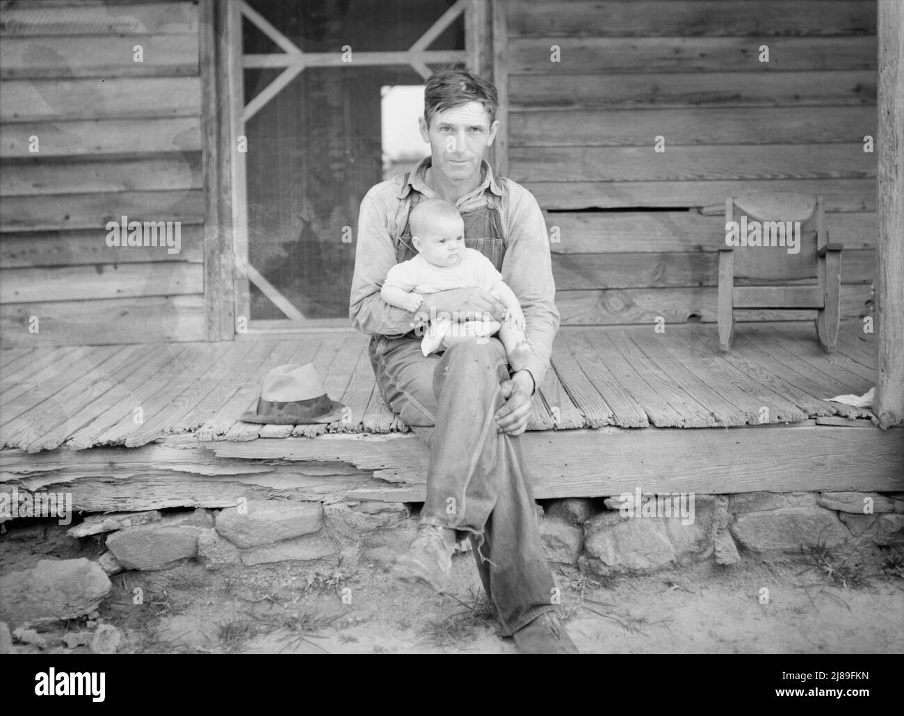 Mr. Whitfield, tobacco sharecropper, with baby on front porch. North Carolina, Person County. Stock Photo