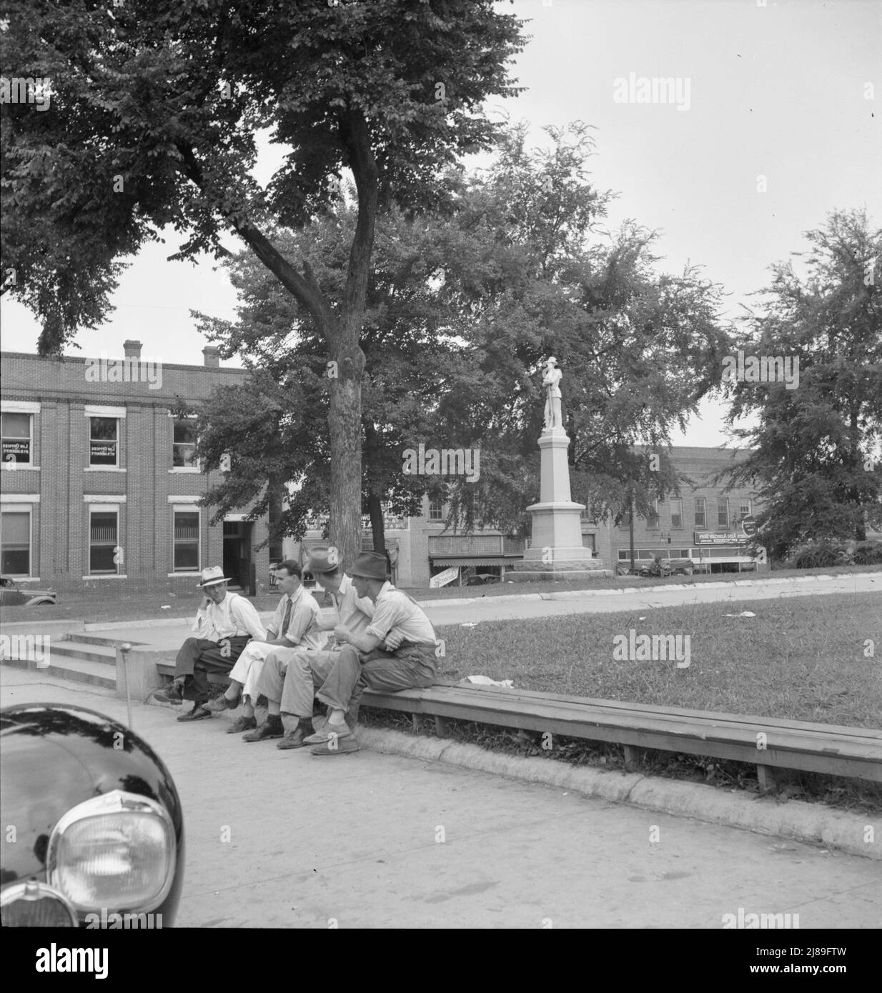 Men idling around the courthouse square. Note Confederate monument characteristic of Southern towns. Roxboro, North Carolina. Stock Photo