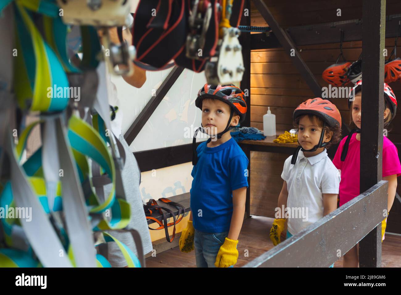 Three little children are examining their equipment and talking. The ...