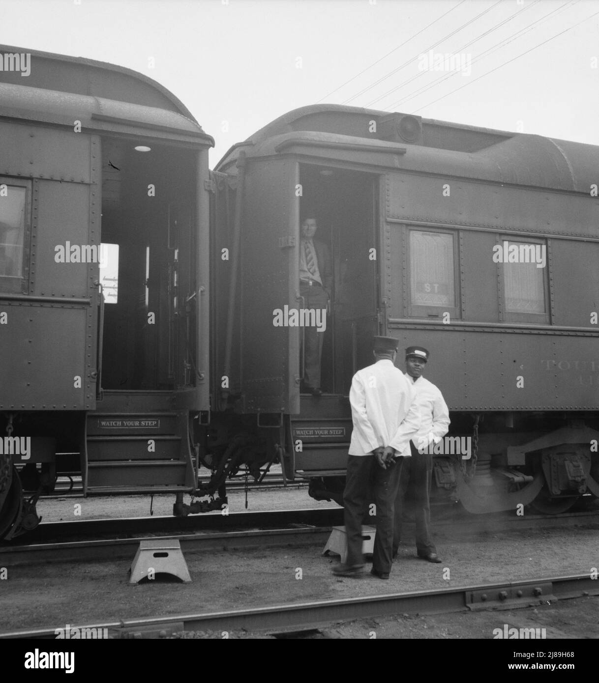 Railroad yards, Kearney, Nebraska. Overland train passengers go back to their cars after ten minute train stop on trip between San Francisco and Chicago. [Black Pullman porters and white passenger]. Stock Photo