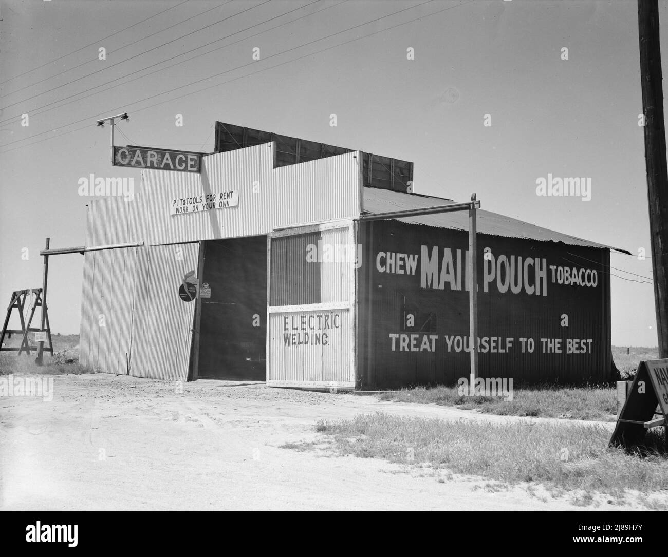 U.S. 99. Fresno County, California. &quot;Pit and tools for rent--work on your own.&quot; California. ['Garage; Electric Welding; Chew Mail Pouch Tobacco - Treat Yourself to the Best']. Stock Photo