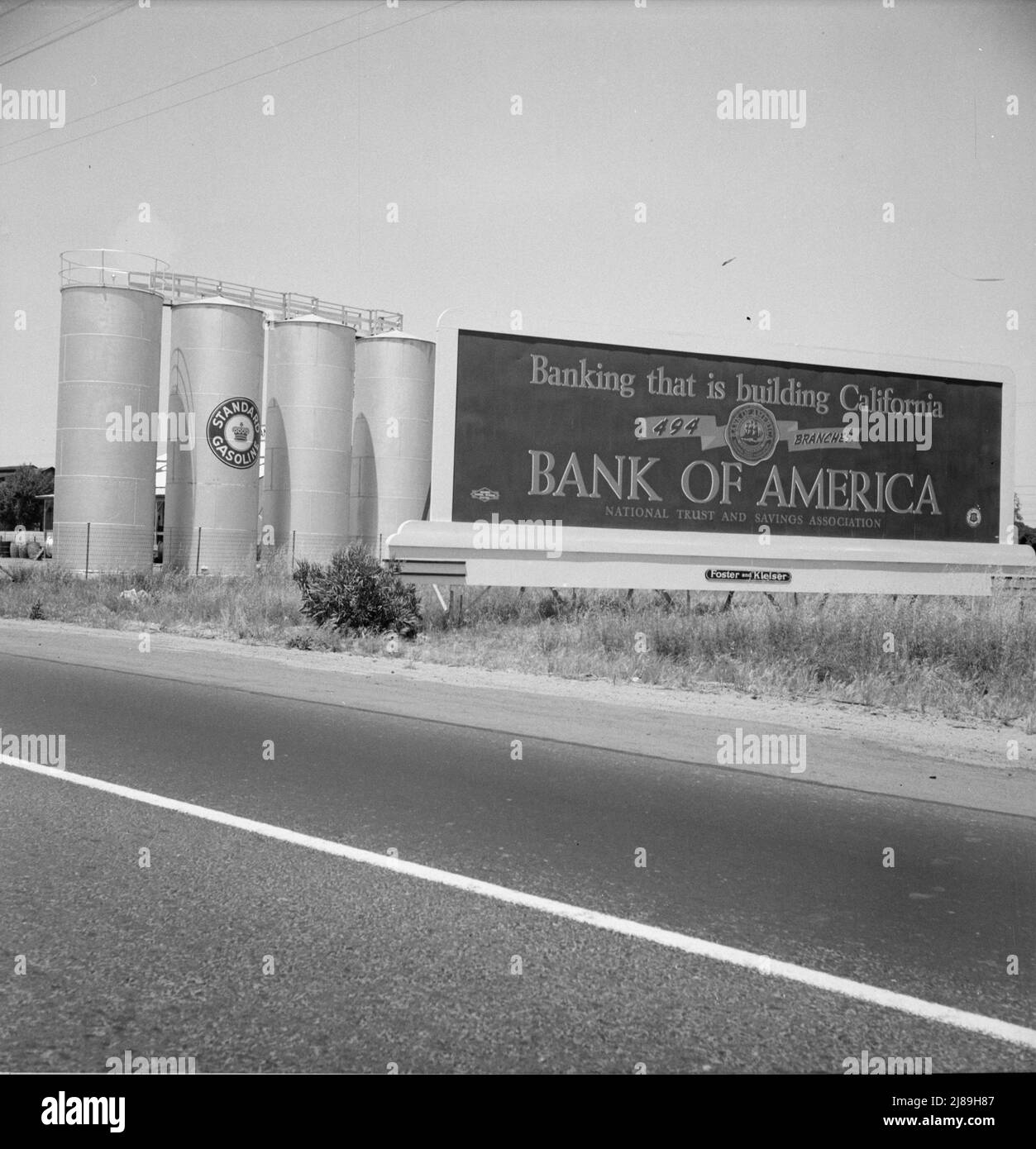 Between Tulare and Fresno on U.S. 99. Highway gas tanks and signboard approaching town. ['Standard Gasoline; Banking that is building California - 494 Branches - Bank of America - National Trust and Savings Association']. Stock Photo